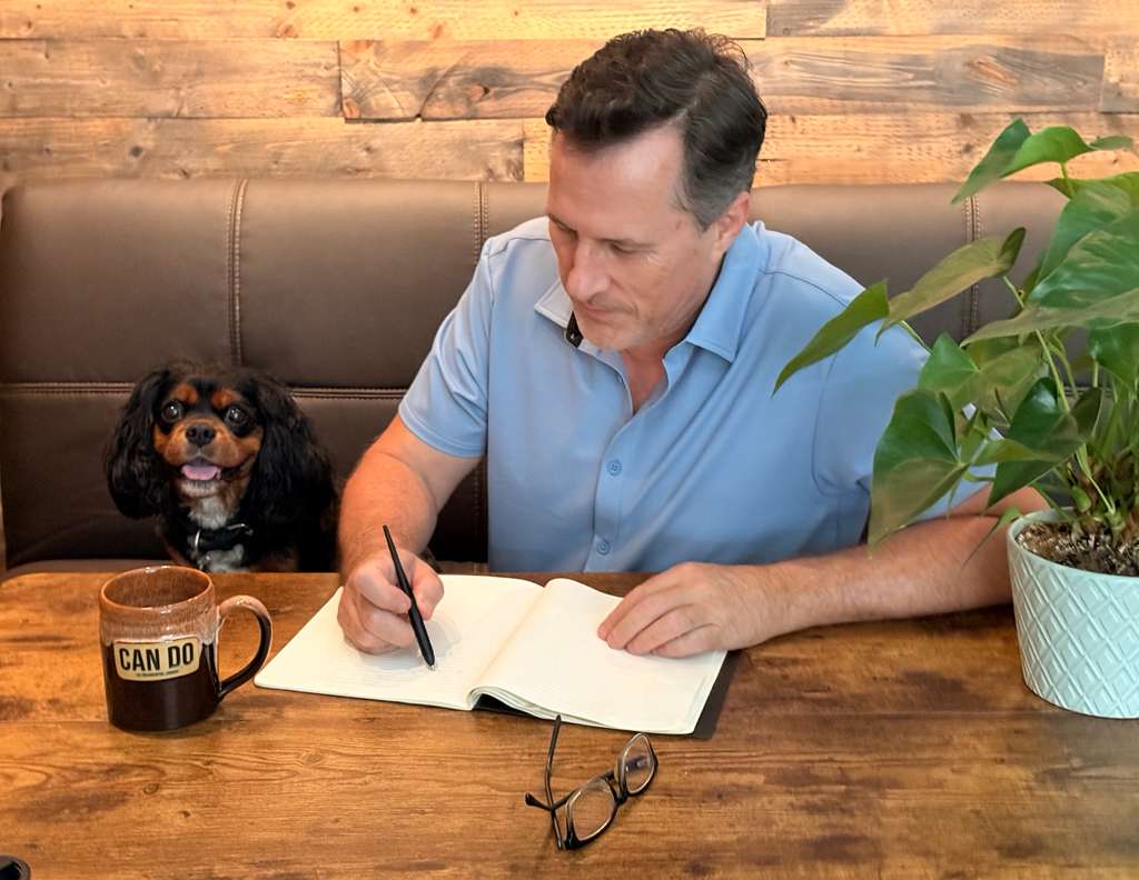 Danny writing at a table with his dog
